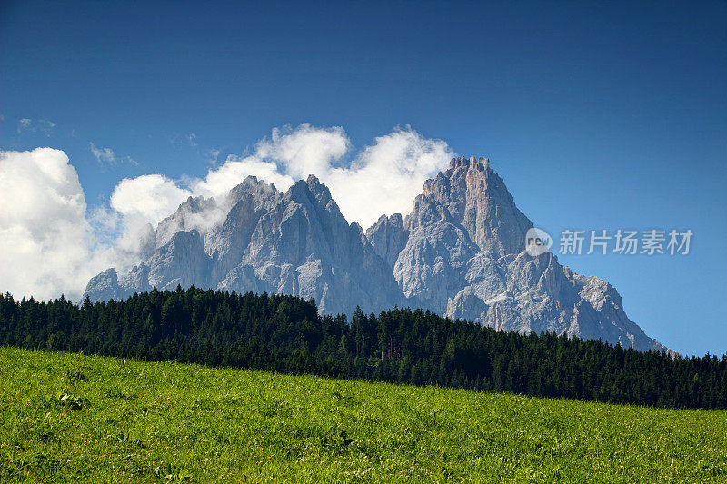 锯齿状的Dolomiti Sesto山峰耸立在森林和阳光灿烂的草地上